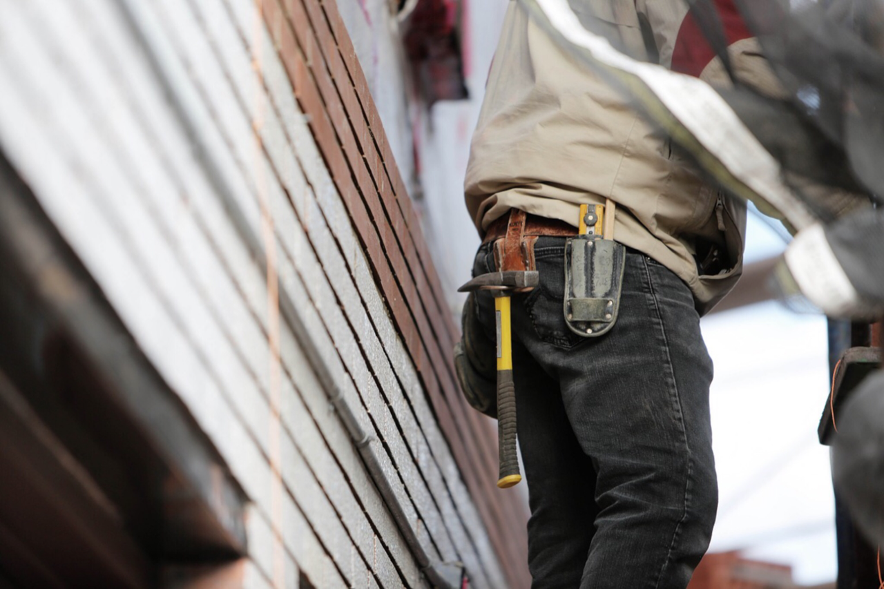Contractor standing outside a home with tool belt in focus
